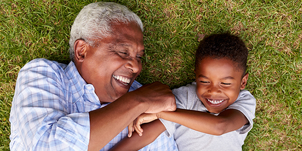 Philadelphia Medicare Health Plan Recipient And Grandson Smiling While Lying On The Grass