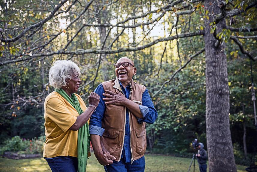 An older couple walking in a park together, laughing