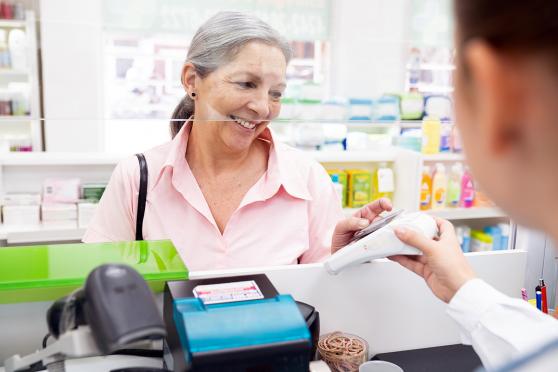 A senior woman pays at the pharmacy