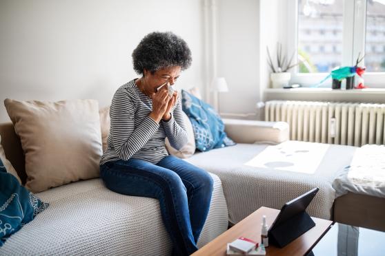 Woman with cold blowing her nose into a tissue