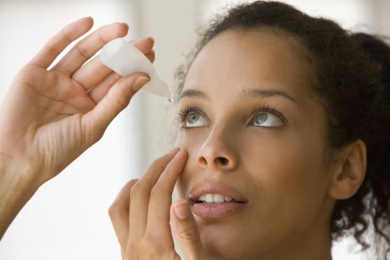 Woman putting eye drops in eye