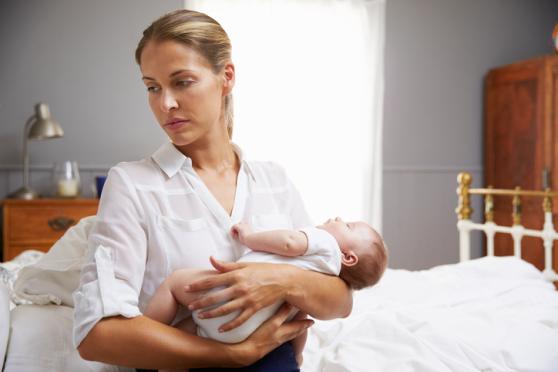 Woman carrying a baby and looking away from him/her