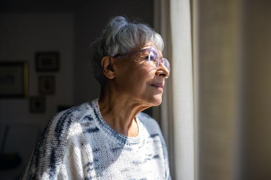 A senior woman looks out a window
