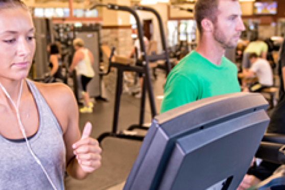 A woman runs on a treadmill at a gym