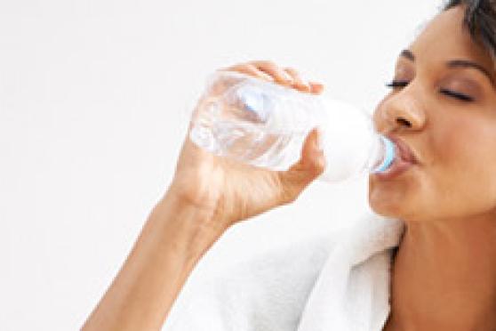 A woman sips from a glass of water