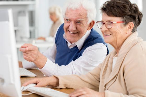 Photo: Senior man and woman smiling and working on computers.